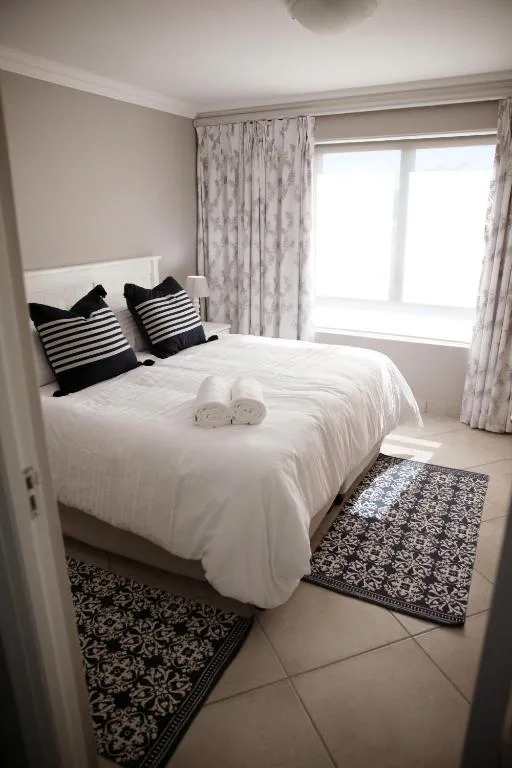 Bright bedroom with white bed, striped pillows, and patterned area rug