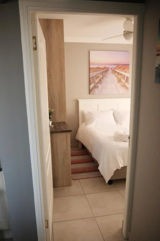 Bright bedroom with white bed and landscape artwork on wall