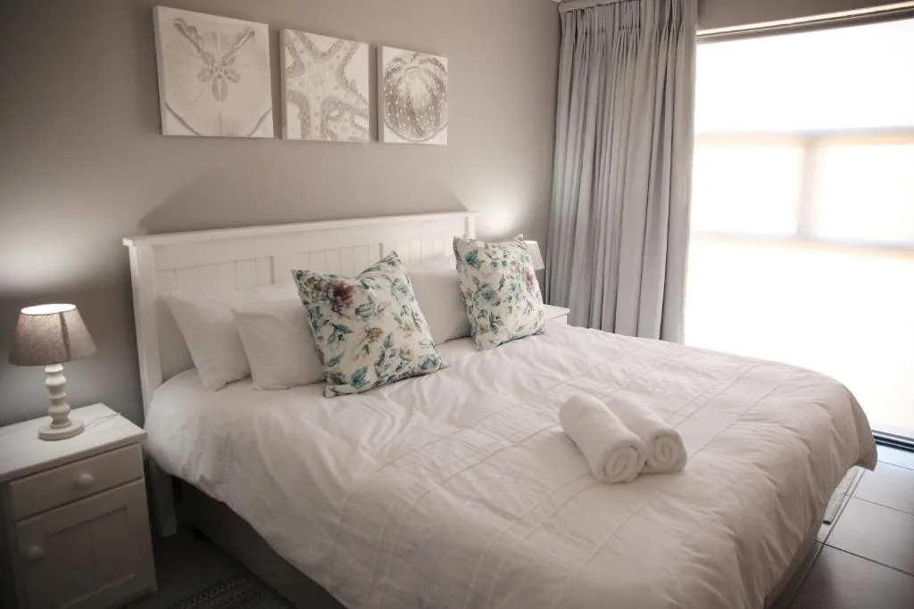 Bright bedroom with white headboard, floral pillows, and rolled towels