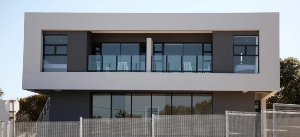 Modern two-story apartment building with gray facade and large windows