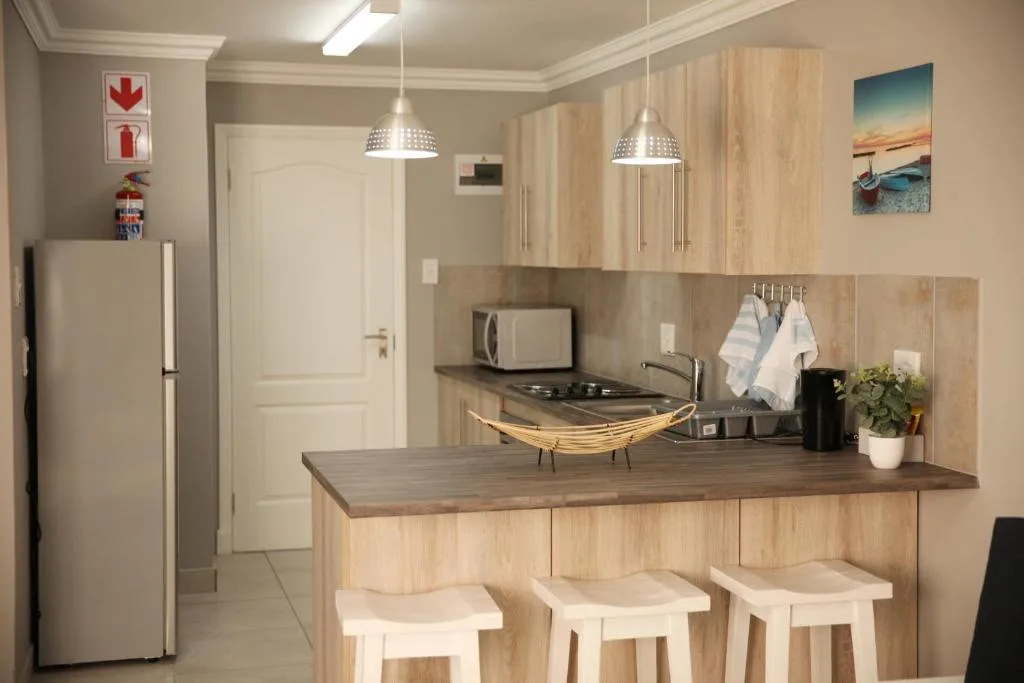 Modern kitchen with light wood cabinetry, dark countertop, and bar seating