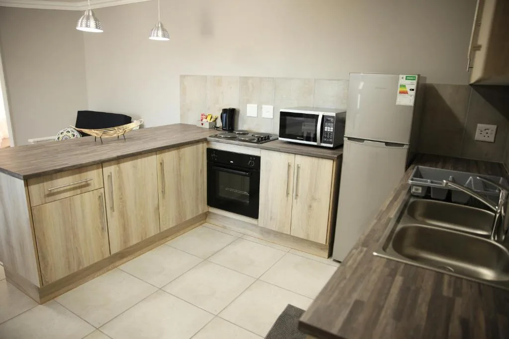 Modern kitchen with light wood cabinetry, black oven, and stainless steel appliances