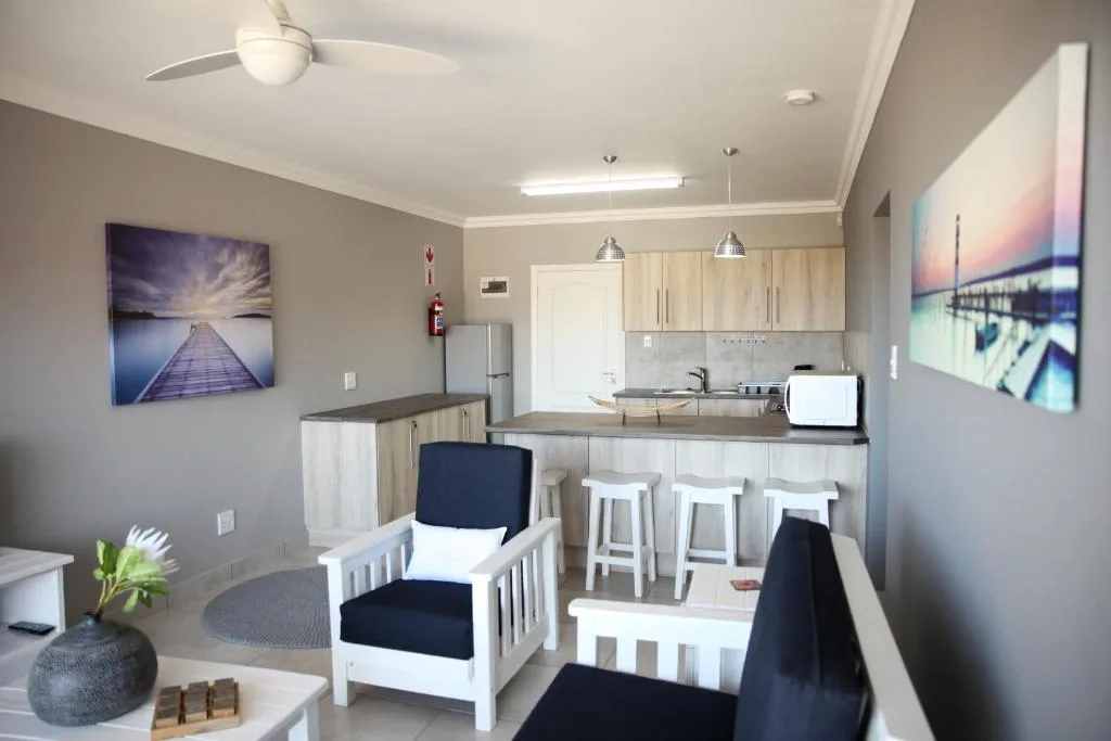 Open-plan lounge and kitchen with white furniture and scenic artwork