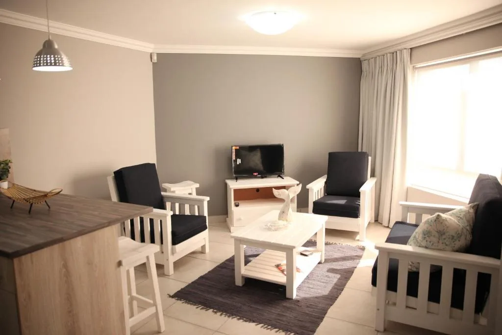 Modern living room with white furniture, flat-screen TV, and comfortable seating