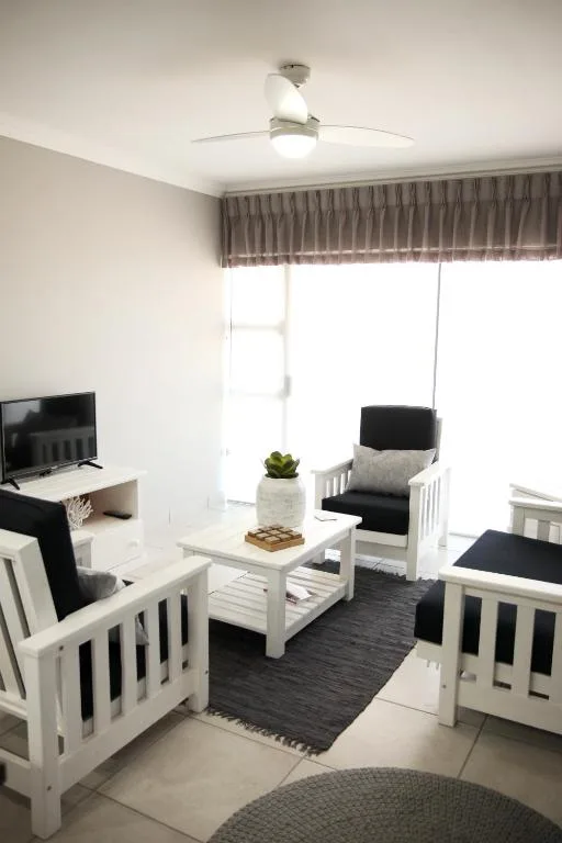 Bright lounge with white furniture, TV, and potted plant decoration