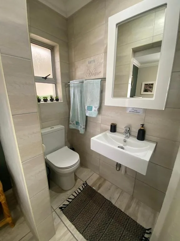 Modern bathroom with toilet, sink, mirror, and shower cubicle