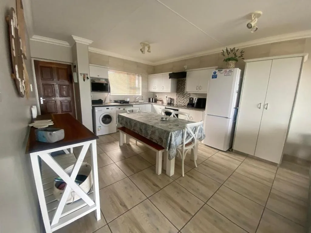 Spacious open-plan kitchen with white cabinetry, dining table, and modern appliances