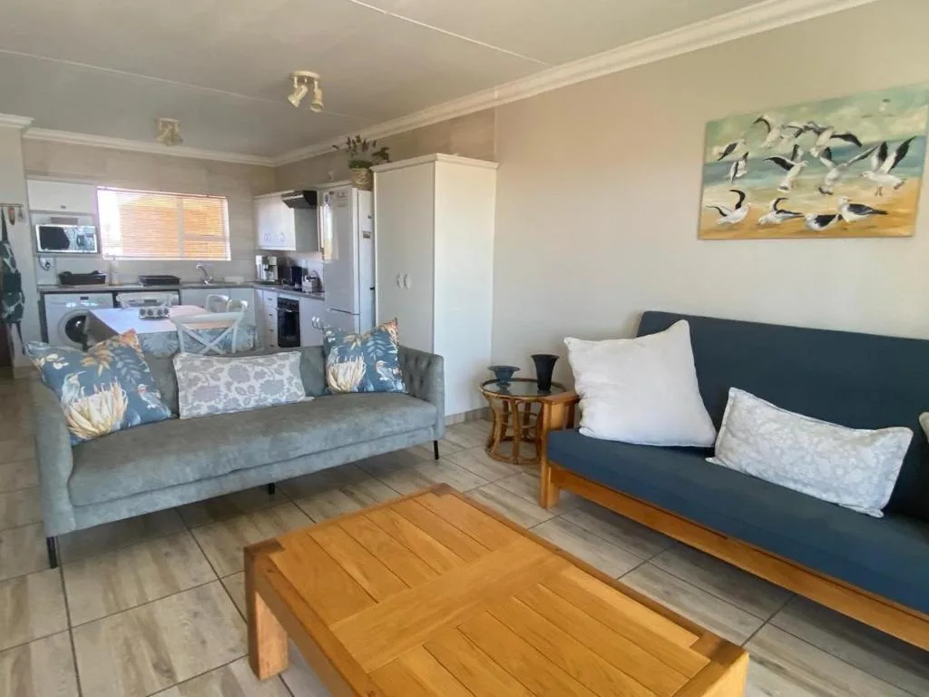 Open-plan lounge with two sofas, coffee table, and kitchen visible beyond