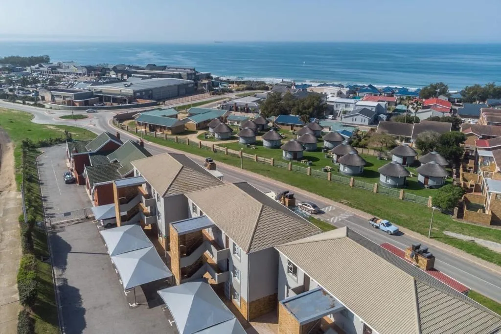 Aerial view of beachfront holiday apartments with ocean and coastal town beyond