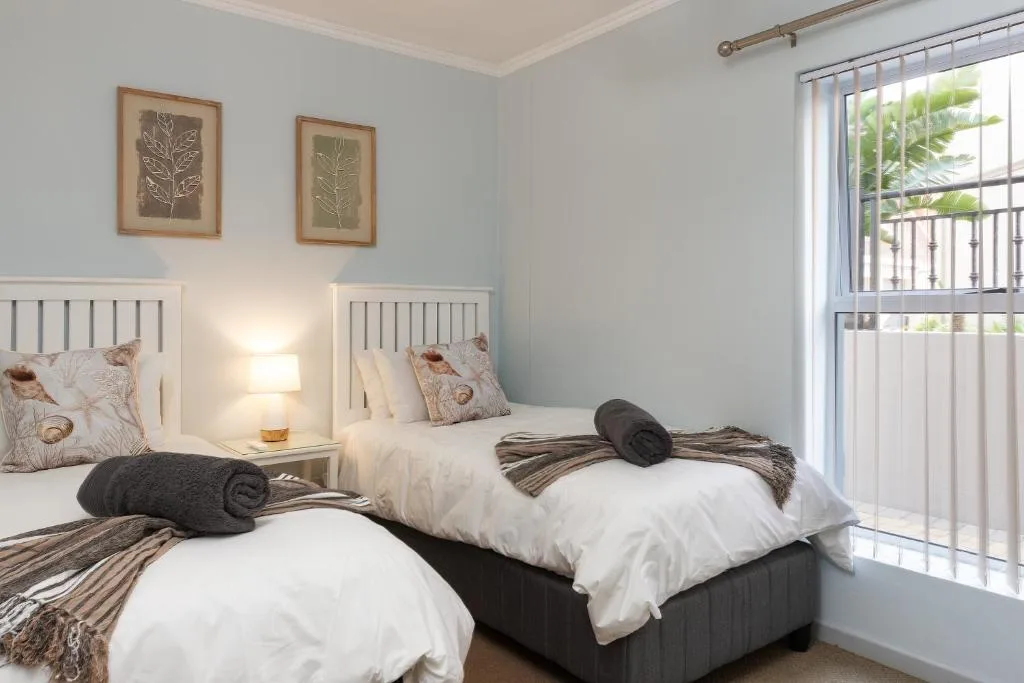 Twin bedroom with white headboards, crisp linens, and garden view through glass doors