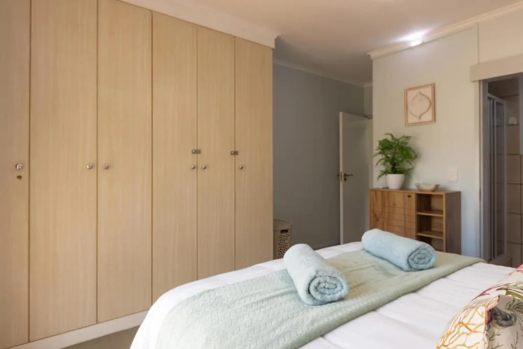 Bright bedroom with double bed, wooden built-in wardrobes, and storage furniture