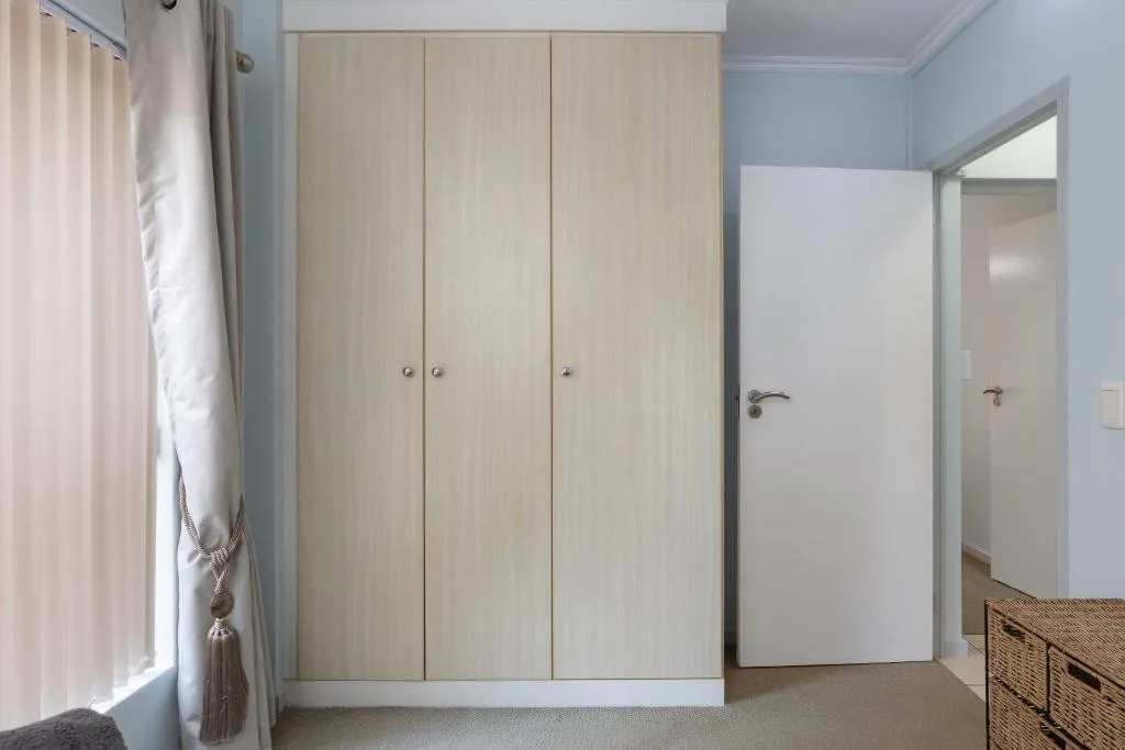 Spacious bedroom with light wood wardrobe and modern furnishings