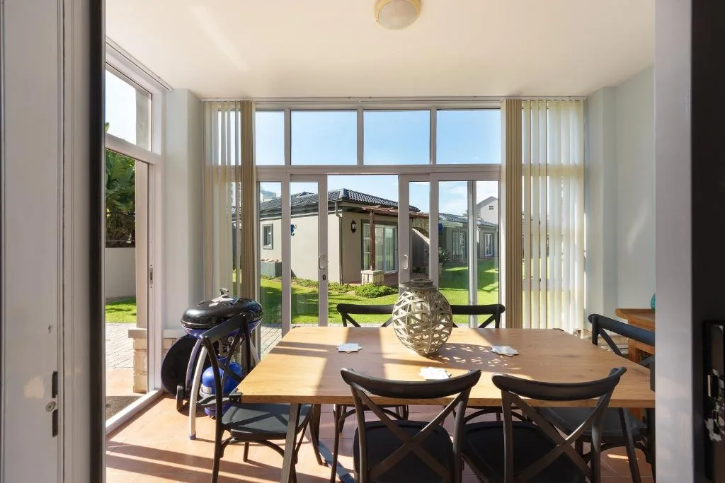 Bright dining area with wooden table, black chairs, garden views