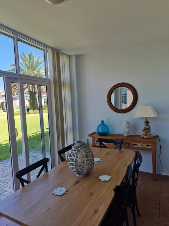 Wooden dining table with black chairs and garden views through glass doors