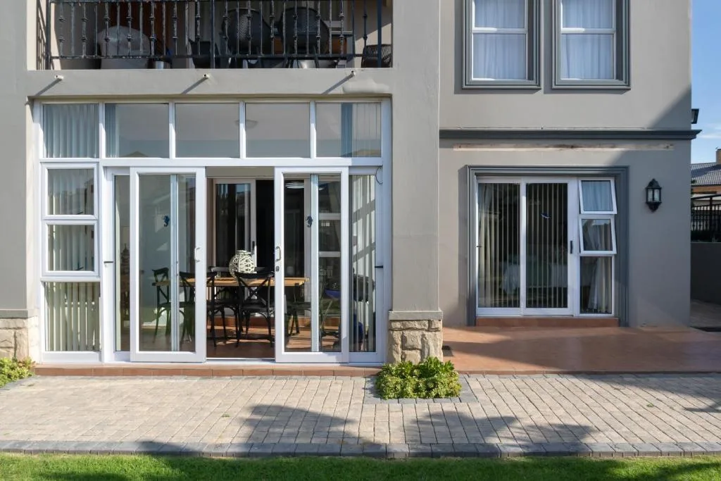 Modern beige apartment facade with large sliding glass doors and paved courtyard
