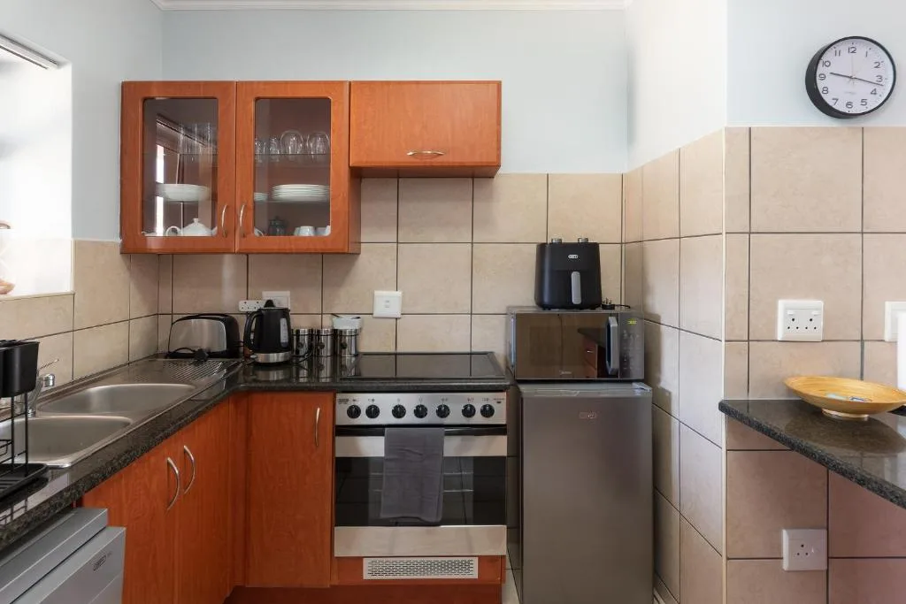 Well-equipped kitchen with orange cabinetry, stainless steel stove, and tiled walls