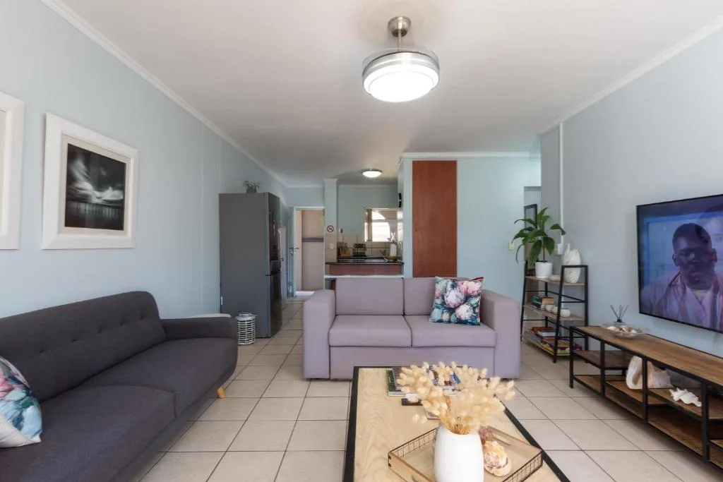 Open-plan living room with purple sofa, dark couch, and flat-screen TV