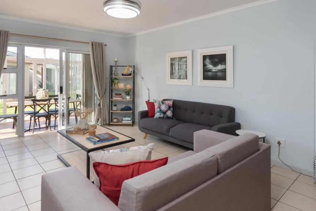 Bright lounge with two sofas, coffee table, and sliding doors to deck