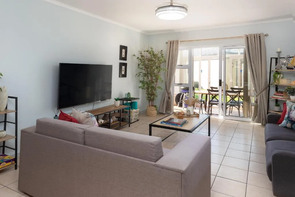 Spacious living room with grey sofa, TV, and glass doors to deck