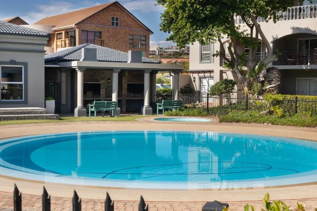 Circular swimming pool with covered patio and green benches nearby