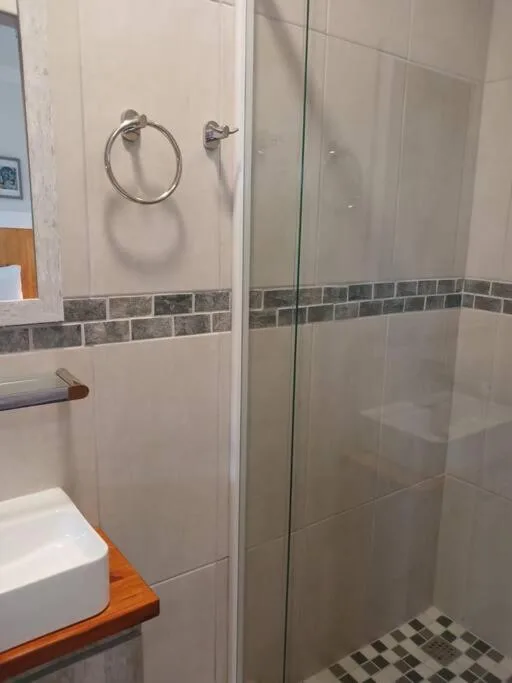 Modern bathroom with glass shower enclosure and tiled accent wall
