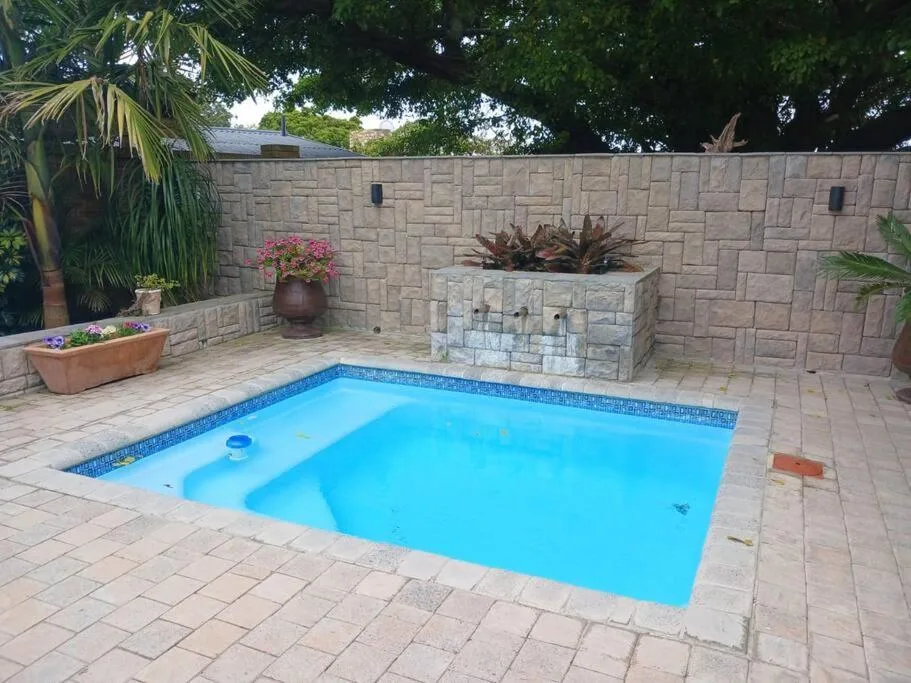 Rectangular swimming pool with blue water surrounded by paved deck and landscaping