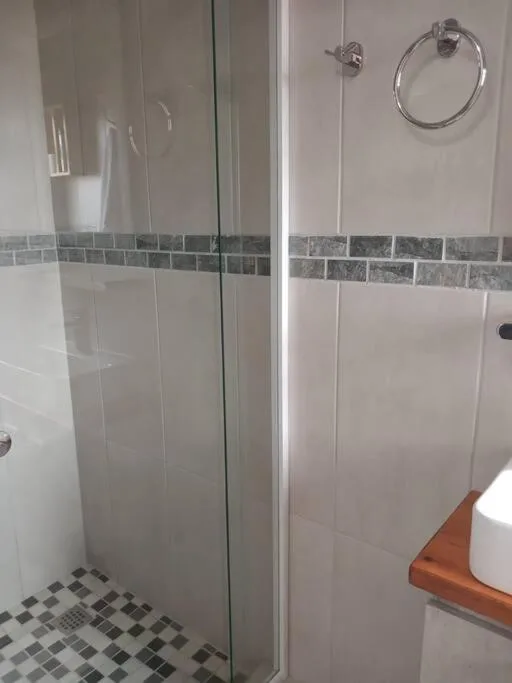 Modern glass-enclosed shower with decorative tile border and chrome fixtures