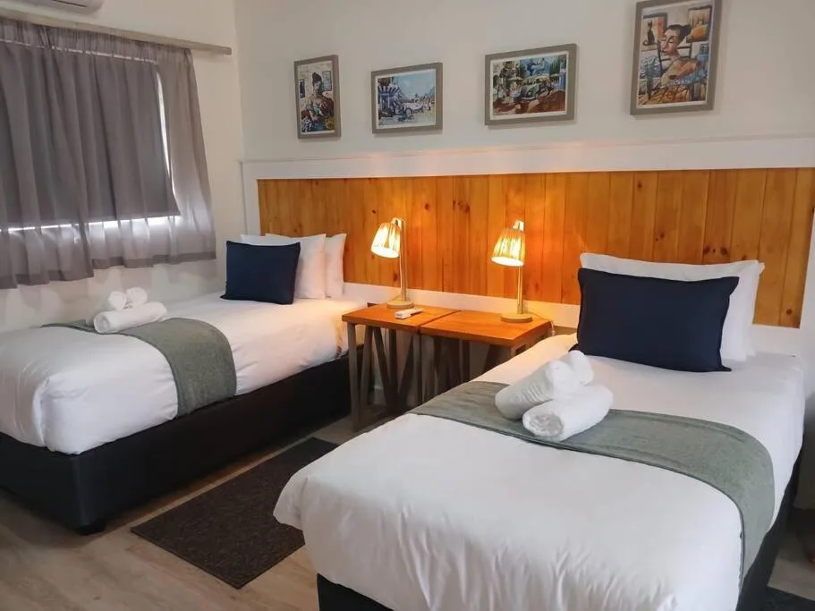 Twin bedroom with wooden headboard, white bedding, and warm lighting