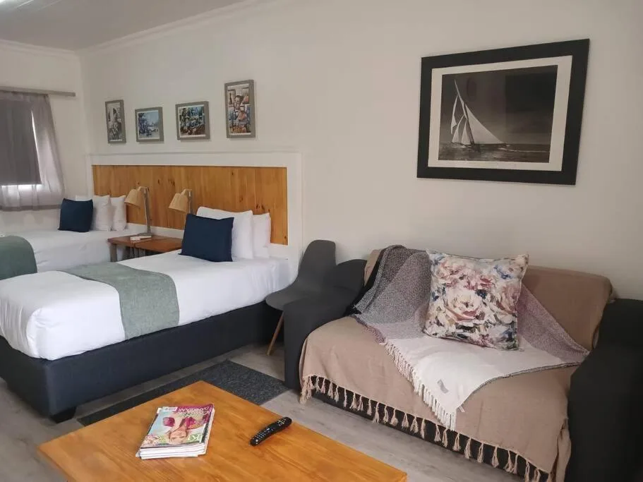 Twin beds with wooden headboard and comfortable seating area in bright room