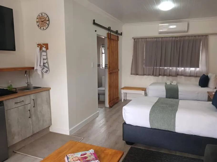 Bright bedroom with two beds, kitchenette, and sliding barn door