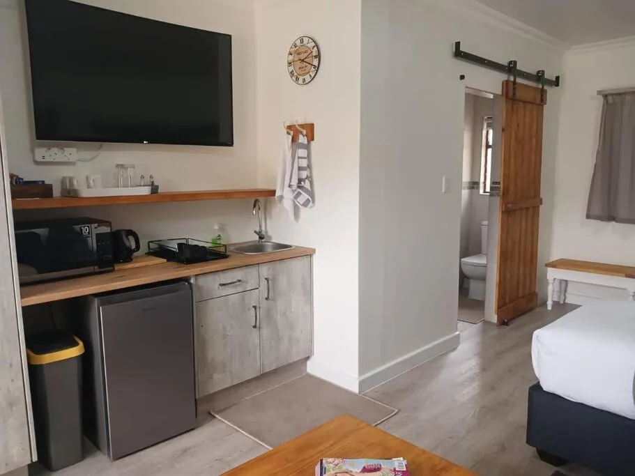 Modern kitchenette with stainless appliances and wooden counters, wall-mounted TV