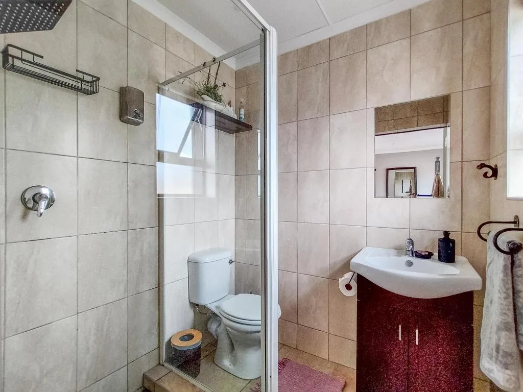 Modern bathroom with walk-in shower, toilet, and burgundy vanity sink