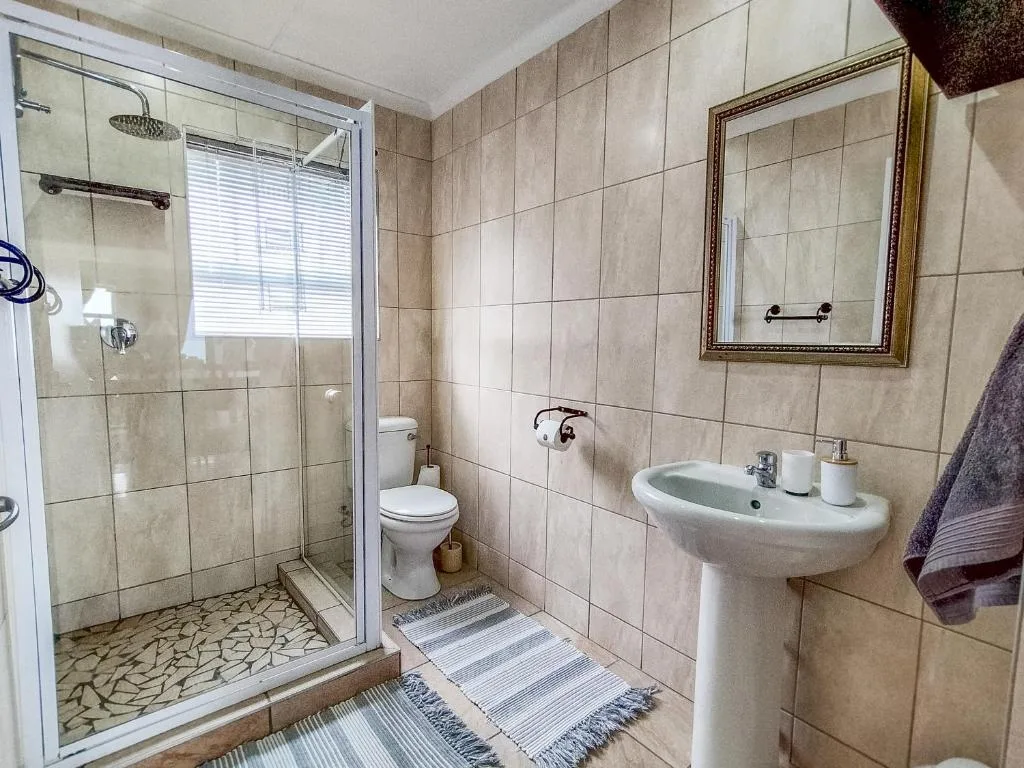 Bathroom with shower, toilet, pedestal sink, and framed mirror
