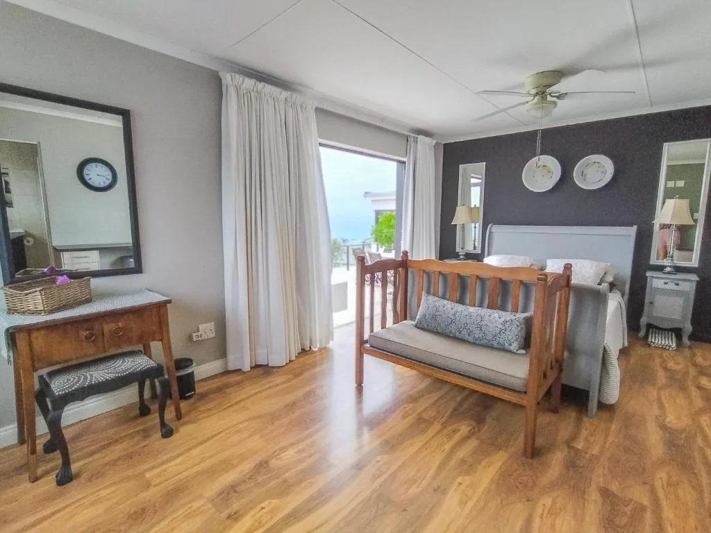 Spacious bedroom with wooden crib, queen bed, ocean view through sliding doors