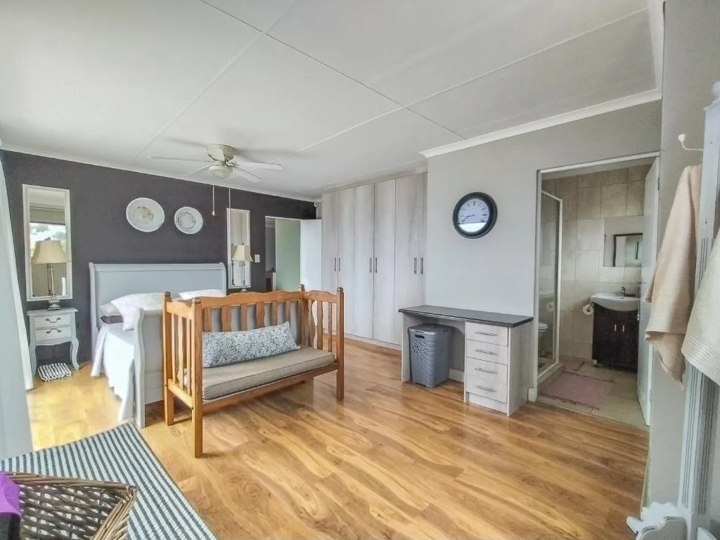 Spacious bedroom with wooden crib, bed, and ensuite bathroom entrance