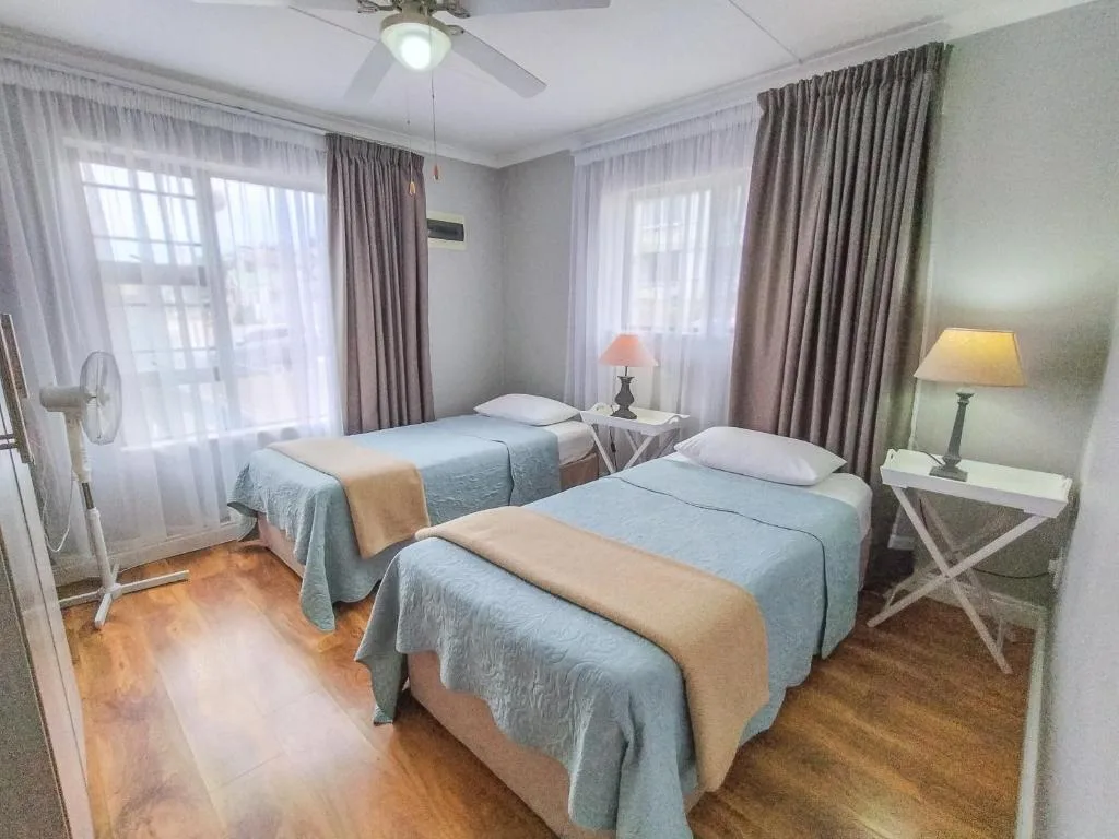 Spacious bedroom with two single beds, large windows, and elegant curtains