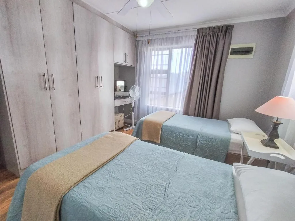 Spacious bedroom with two beds, built-in wardrobes, and garden view