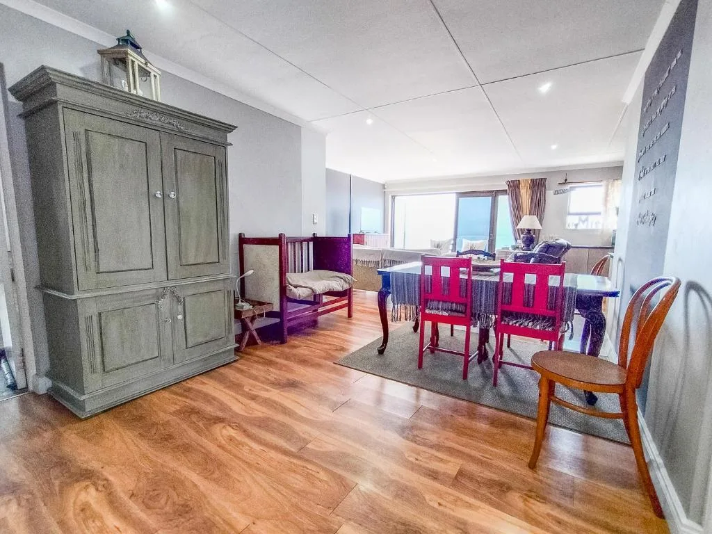 Spacious bedroom with wooden flooring, antique wardrobe, and vintage red chairs