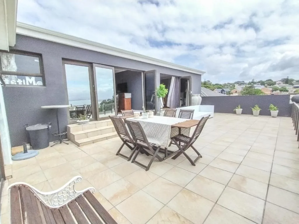 Spacious rooftop terrace with dining table, loungers, and ocean views