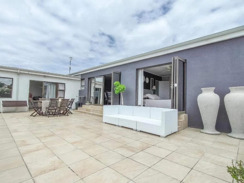 Modern patio with white seating, potted plants, and ocean views