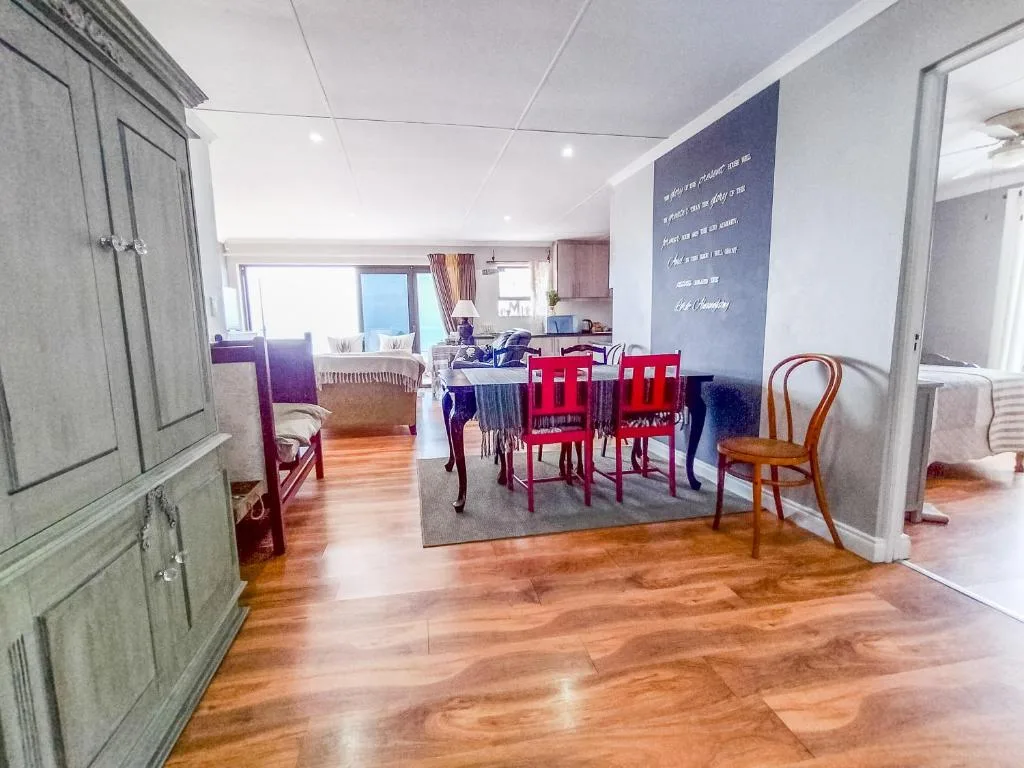 Open-plan dining area with red chairs and wooden table in modern apartment