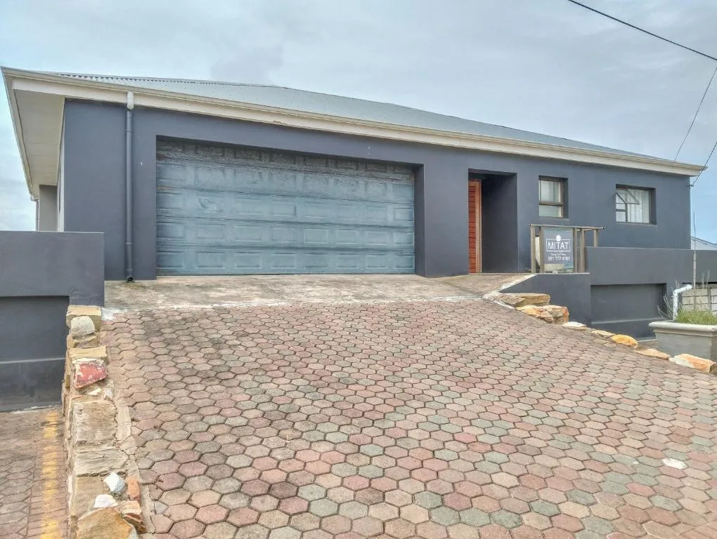 Modern dark-facade home with turquoise garage door and brick driveway