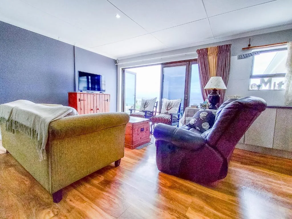 Open-plan lounge with purple armchair, upholstered seating, and ocean view windows
