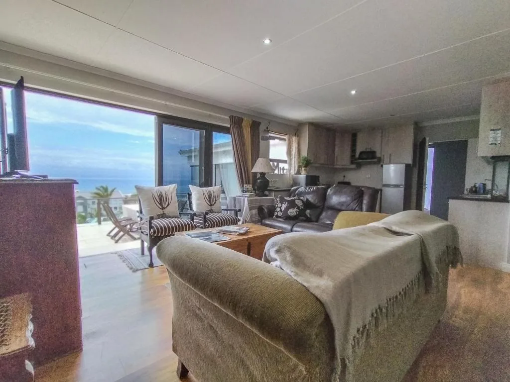 Open-plan lounge with ocean view, leather sofa, and coastal landscape