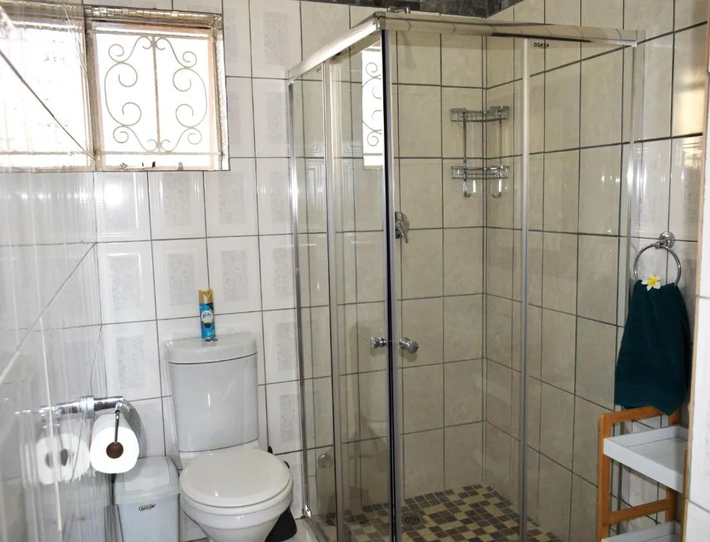 Clean bathroom with enclosed shower stall, toilet, and tiled walls