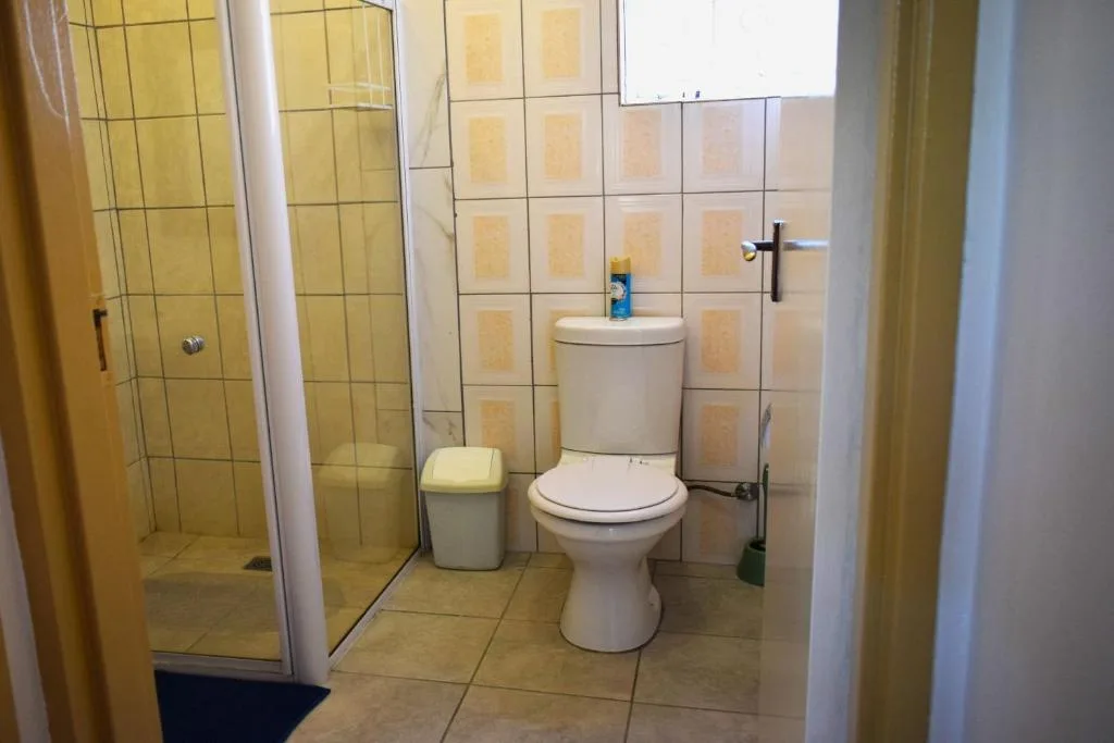 Bathroom with toilet, shower enclosure, and cream tile walls