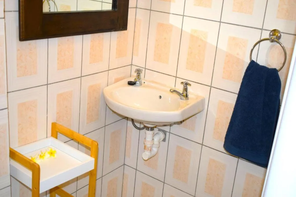 Bathroom vanity with dual sinks and peach-toned tiled walls