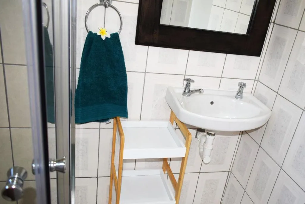 Clean bathroom with white sink, mirror, and teal towel on rack