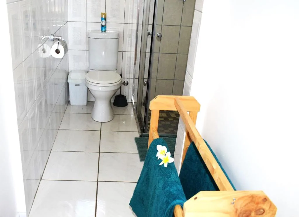 Clean bathroom with toilet, tiled walls, shower enclosure, and toilet roll holder