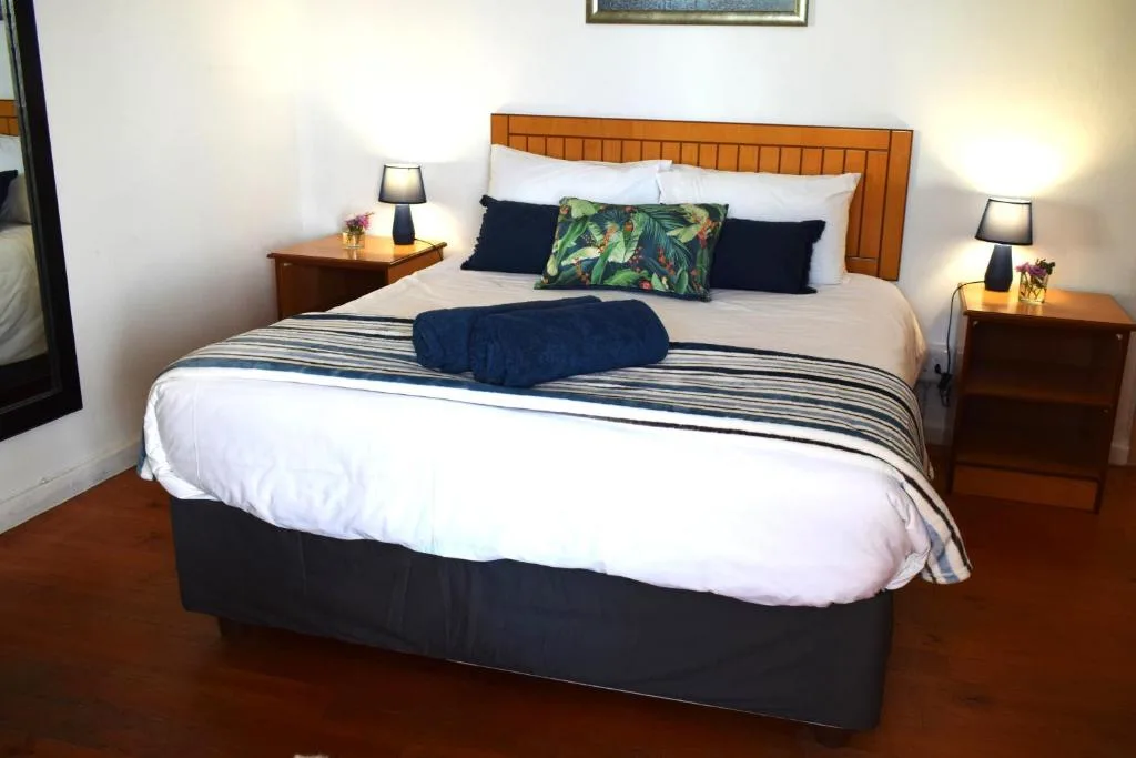 Spacious bedroom with queen bed, wooden headboard, side tables, and lamps